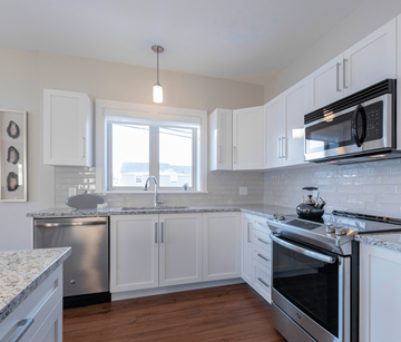 Dieppe apartment for rent - A kitchen with white cabinets and a stainless steel dishwasher.
