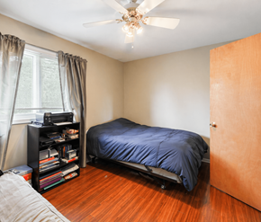 Moncton apartment for rent - A bedroom with a bed, a ceiling fan, and a bookshelf.