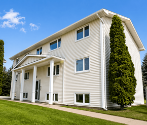 Moncton apartment for rent - A white house with a grey roof and a tree in front.