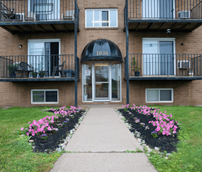 Moncton apartment for rent - The front of apartment building number 1636 with a walkway and flower beds.