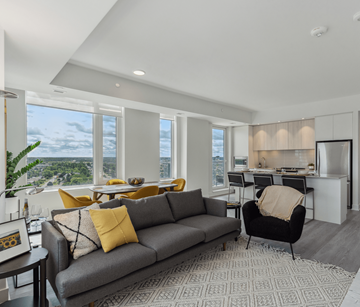 Ottawa apartment for rent - A grey couch with yellow pillows sits in a living room with a view of the city.
