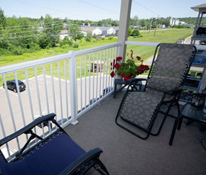 Fredericton apartment for rent - A chair and a table with a flower pot on a balcony.