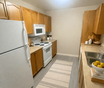Fredericton apartment for rent - A kitchen with a white refrigerator, white stove, and wooden cabinets.