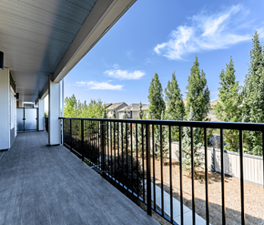 Edmonton apartment for rent - A balcony with a black railing and a view of trees and houses.