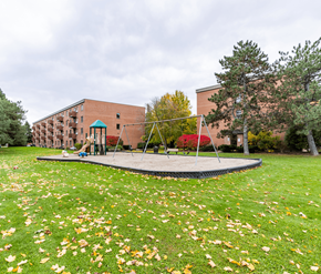 Waterloo apartment for rent - A playground with a trampoline and a slide in front of a brick building.