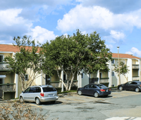 St. Johns apartment for rent - A silver minivan is parked in a parking lot in front of a white apartment building.