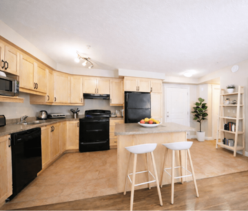 Dieppe apartment for rent - A kitchen with wooden cabinets and black appliances.