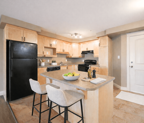 Dieppe apartment for rent - A kitchen with a black fridge, white chairs, and a marble countertop.