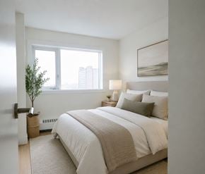 Halifax apartment for rent - A bedroom with a large bed and a small tree by the window.