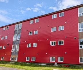 St. Johns apartment for rent - A red building with white windows and a blue sky in the background.