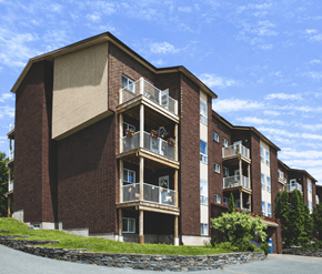 St. Johns apartment for rent - A large brick building with balconies and a stone wall in front.