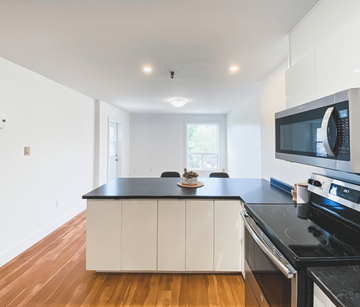 St. John's apartment for rent - A kitchen with white cabinets and black countertops.