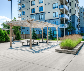 Cambridge apartment for rent - A patio area with a table and benches under a pergola in front of a building.