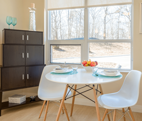 Cambridge apartment for rent - A dining room with a white table and chairs, a cabinet, and a view of trees outside the window.