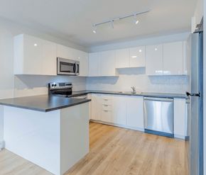 Fredericton apartment for rent - A modern kitchen with white cabinets and a black countertop.