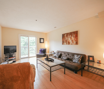 Fredericton apartment for rent - A living room with a brown couch and a glass coffee table.