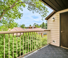 Calgary apartment for rent - A balcony with a view of a house and trees.