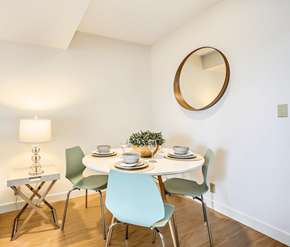Calgary apartment for rent - A white dining table with four chairs and a small plant on it.