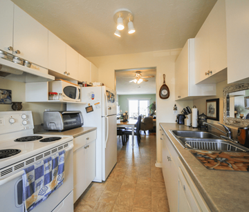Riverview apartment for rent - A kitchen with white cabinets and a checkered towel on the stove.