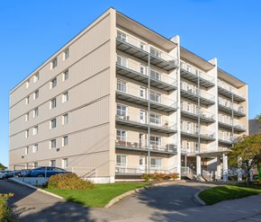 Saint John apartment for rent - A large apartment building with a parking lot in front.
