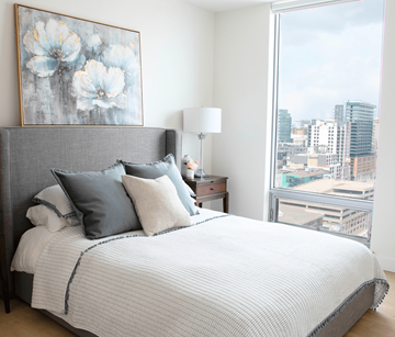 Halifax apartment for rent - A bedroom with a large bed and a city view through the window.