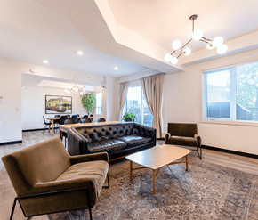 Edmonton apartment for rent - A living room with a black couch, brown armchair, and a wooden coffee table.