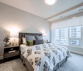 Mississauga apartment for rent - A bedroom with a large bed and a window overlooking a cityscape.
