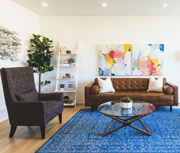 St. John's apartment for rent - A living room with a brown couch, a brown chair, a glass coffee table and a blue rug.