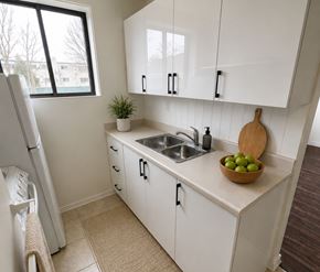 London apartment for rent - A kitchen with white cabinets and a bowl of green apples on the counter.