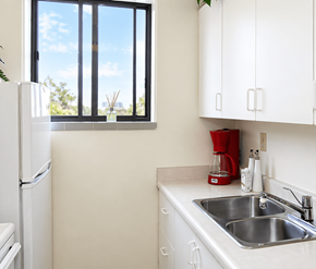 London apartment for rent - A kitchen with a white fridge, white cabinets, and a window.