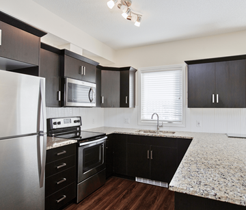 Calgary apartment for rent - A kitchen with black cabinets and a granite countertop.