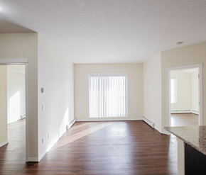 Calgary apartment for rent - A large empty room with wooden floors and white walls.