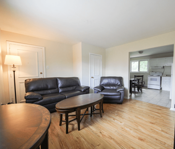 Fredericton apartment for rent - A living room with a black leather couch and a wooden table.