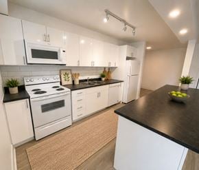 London apartment for rent - A modern kitchen with white cabinets and black countertops.