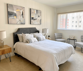 Kanata-Ottawa apartment for rent - A bedroom with a large bed and two abstract paintings on the wall.