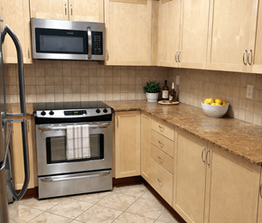 Kanata-Ottawa apartment for rent - A kitchen with a stainless steel oven and microwave above a counter with a bowl of lemons on it.