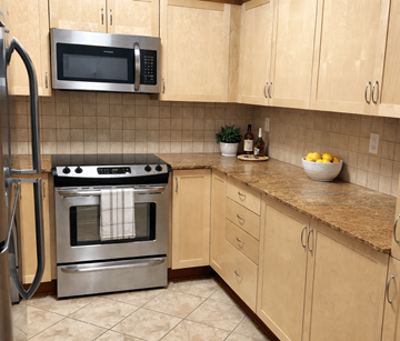Kanata-Ottawa apartment for rent - A kitchen with a stainless steel oven and microwave above a counter with a bowl of lemons on it.
