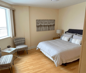 Kanata Ottawa apartment for rent - A bedroom with a bed, chair, and painting on the wall.