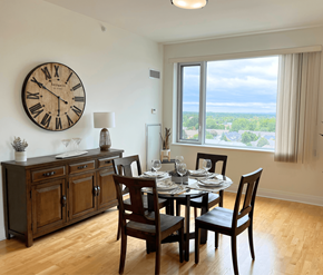 Kanata Ottawa apartment for rent - A dining room with a table set for four and a large clock on the wall.