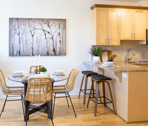 Kanata-Ottawa apartment for rent - A kitchen with a table set for two and a painting of trees on the wall.