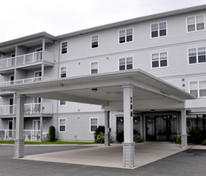 Fredericton apartment for rent - A large building with a covered walkway in front.