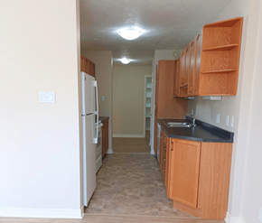 Fredericton apartment for rent - A kitchen with a white refrigerator and wooden cabinets.