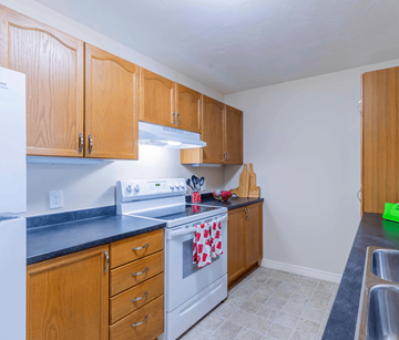 Fredericton apartment for rent - A kitchen with wooden cabinets and a white stove top oven.