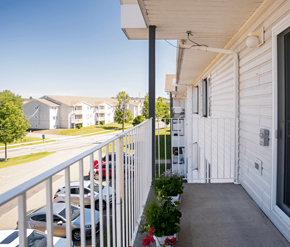 Fredericton apartment for rent - A white house with a balcony overlooking a parking lot.