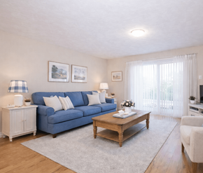 Fredericton apartment for rent - A living room with a blue couch, a wooden coffee table, and a white chair.
