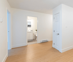 Saint John apartment for rent - A white room with a door and a kitchen in the background.