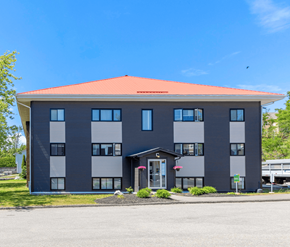 Saint John apartment for rent - A grey building with a red roof and a white door.