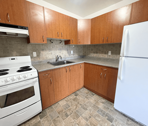 Victoria apartment for rent - A kitchen with white appliances and wooden cabinets.