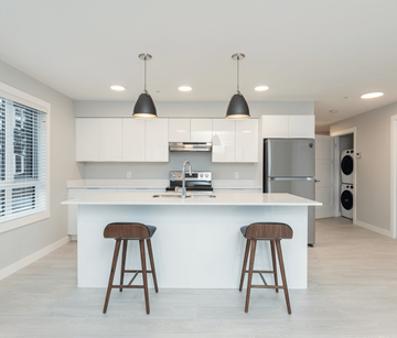 Courtenay apartment for rent - A modern kitchen with white cabinets and a large island with two stools.