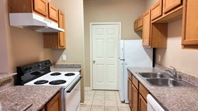 Vidor apartment for rent - A kitchen with a black stove top oven, a white refrigerator, and wooden cabinets.